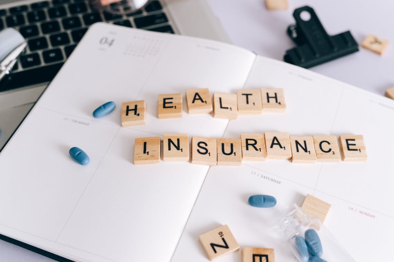 The Art of Drawing Readers In: Your attractive post title goes here Scrabble tiles spelling Health Insurance on planner with pills and laptop, symbolizing healthcare planning.